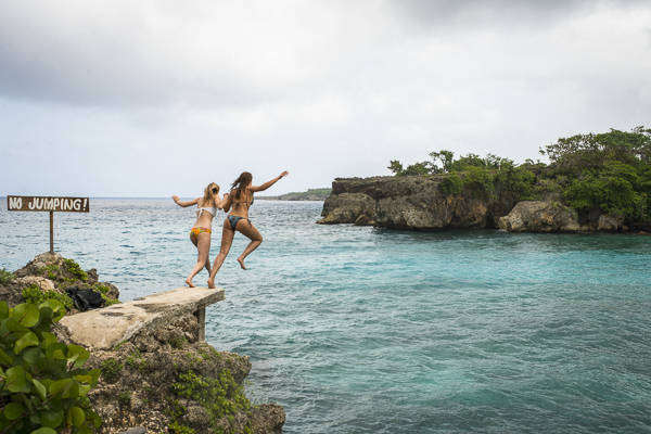 Girls jumping into tropical waters of Boston Bay in Jamaica